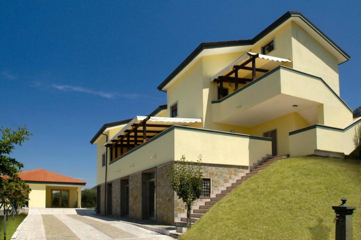 Ein mehrstöckiges Haus mit einer Stein-Fassade und einem roten Ziegeldach, mit einer Treppe, die zu den oberen Stockwerken führt.