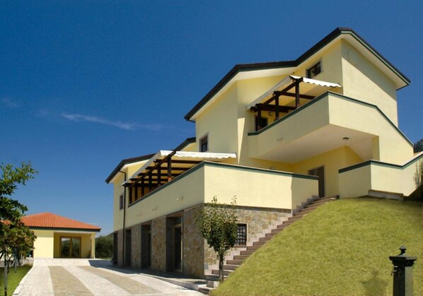 A multi-story house with a stone facade, a red-tiled roof, and a staircase leading to the upper floor. - Residenza Giancesare Family Apartments (Capaccio-Paestum)
