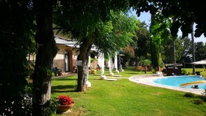 A pool area with a circular pool, surrounded by a well-maintained lawn and trees. - Residenza Giancesare Family Apartments (Capaccio-Paestum)