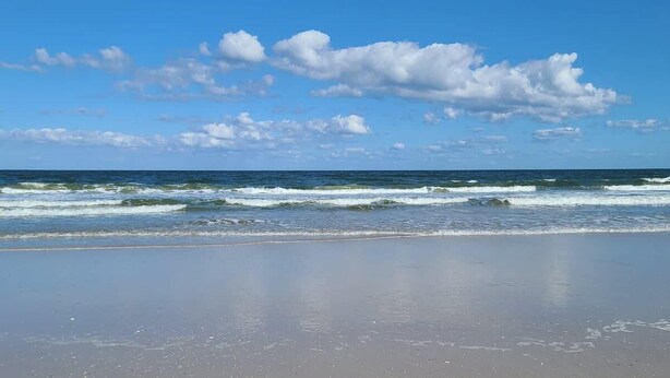 Ein Strand mit Wellen und blauem Himmel.
