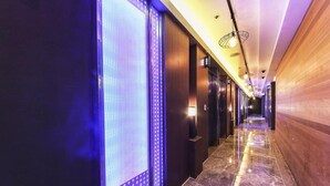 A corridor with a polished marble floor, wooden paneling on one side, and a blue-lit wall on the other. - hwamyeong sky hotel (Busan)