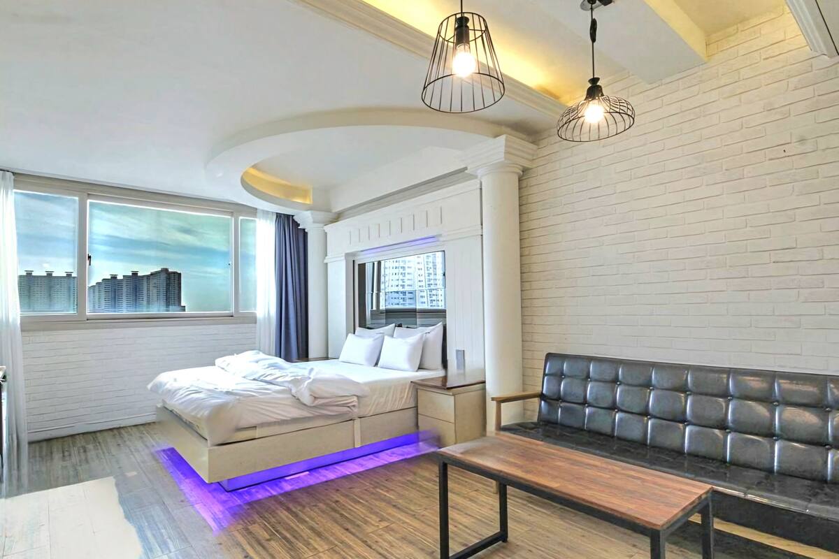 A modern bedroom with a bed, a bench, and a sofa.