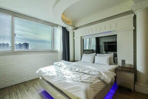 Una habitación de hotel moderna con una cama grande, televisión y vistas a la ciudad.