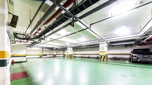 A multi-level parking garage with green flooring, white walls, and yellow safety lines. - hwamyeong sky hotel (Busan)