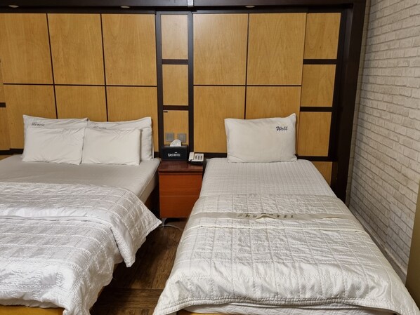 Habitación doble con dos camas, cada una con una almohada y una mesita de noche con un teléfono y una caja que dice "Sky Motel".