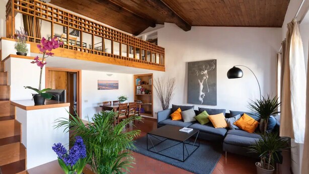 Ein geräumiger Wohnbereich mit Holzboden, einer Sofagarnitur, einem Couchtisch und einer Treppe, die in einen oberen Bereich führt.