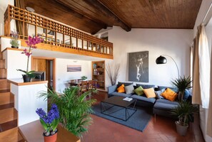 A spacious living area with a wooden ceiling, a sofa set, a coffee table, and a staircase leading to an upper level. - 3-Bedroom Apartment in Florence (Firenze)