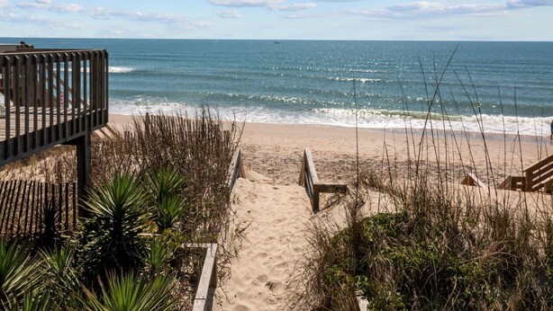 A beach with a wooden walkway leading to the water, surrounded by vegetation. - Ocean Views. Clean! Pup Friendly. 2 Min Walk to the Beach. Beach Gear Included (Surf City)