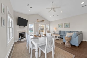 A spacious living room with a fireplace, a dining area, and a blue sofa.