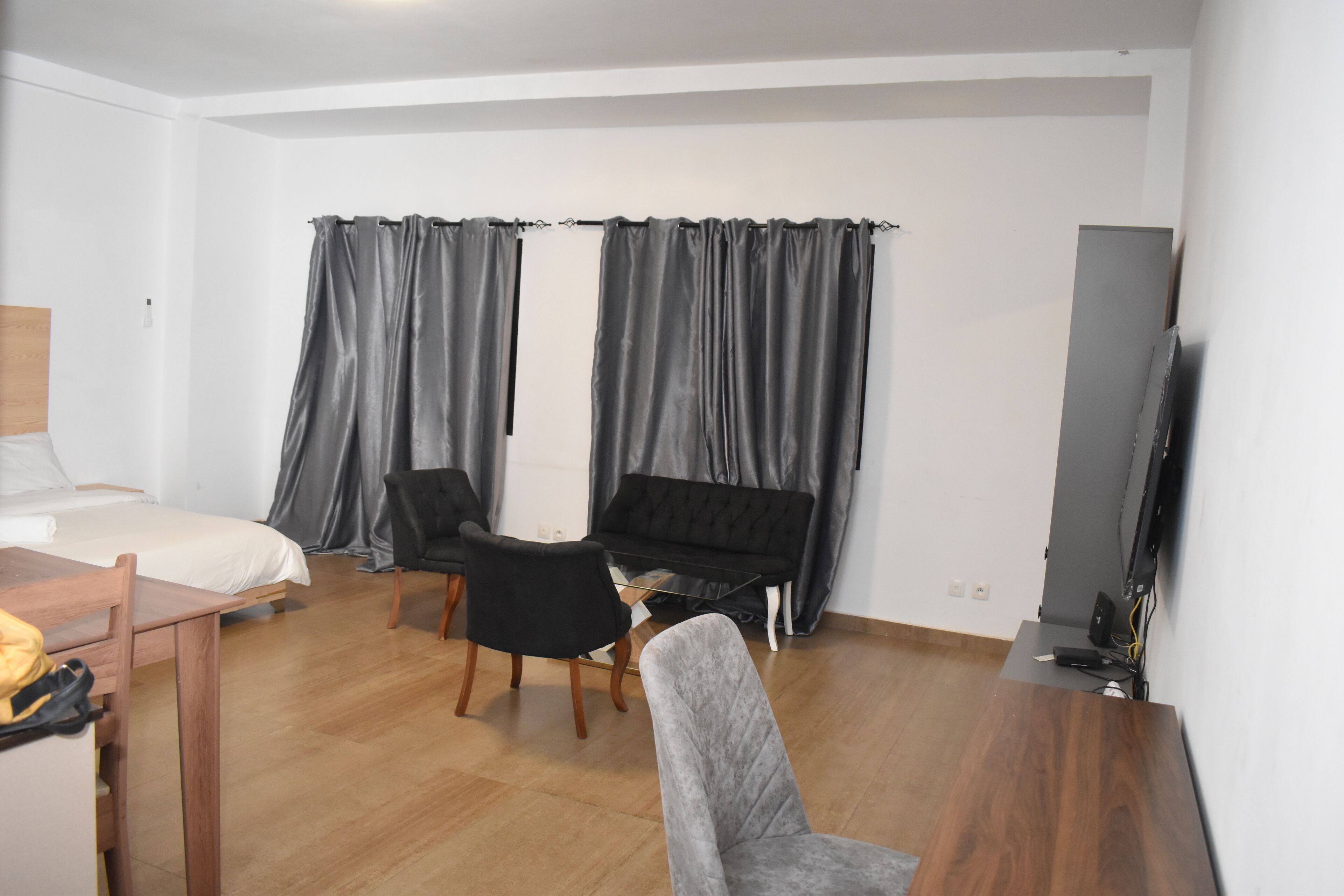 Ett modernt hotellrum med en säng, ett skrivbord, två stolar, en soffa och en TV.
