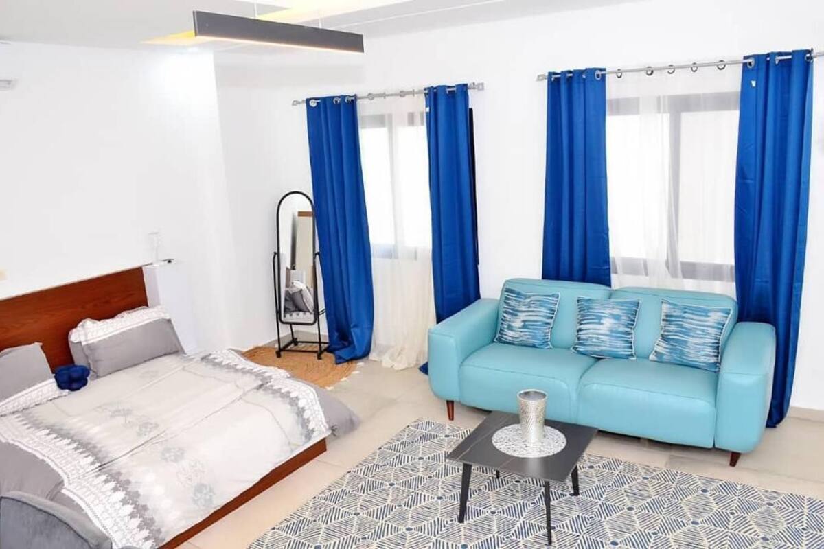 A modern bedroom with a bed, a blue sofa, and a small table.