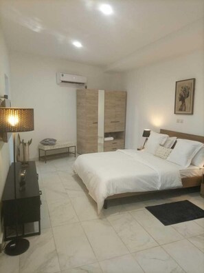 Un dormitorio con cama, mesitas de noche, armario y aire acondicionado.