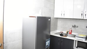 A kitchen with a stainless steel refrigerator, a sink, and white cabinets. - Residence Holi (Abidjan)