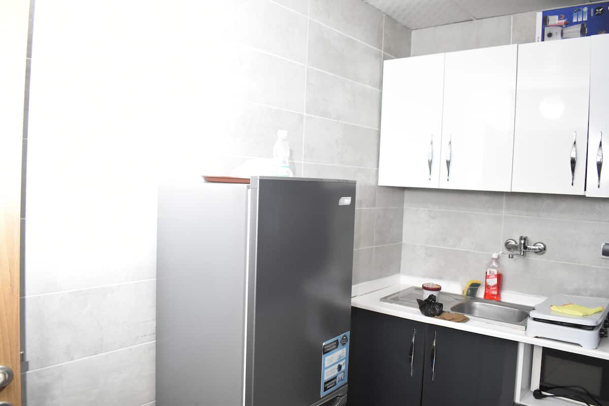 A kitchen with a stainless steel refrigerator, a sink, and white cabinets.