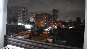 A nighttime cityscape with tall buildings and a busy street. - Residence Holi (Abidjan)