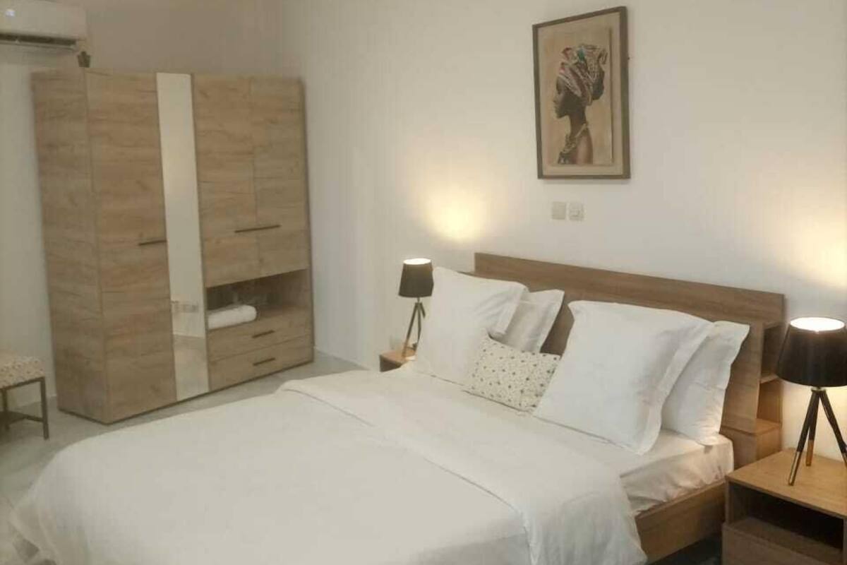 A bedroom with a bed, bedside tables, a wardrobe, and a wall-mounted artwork.