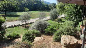 A garden with a gravel path, various shrubs, and a view of a forested area. - La Bastide de Montferrat (Montferrat)