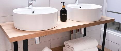 A bathroom with two round white sinks, a wooden vanity, and a mirror above.