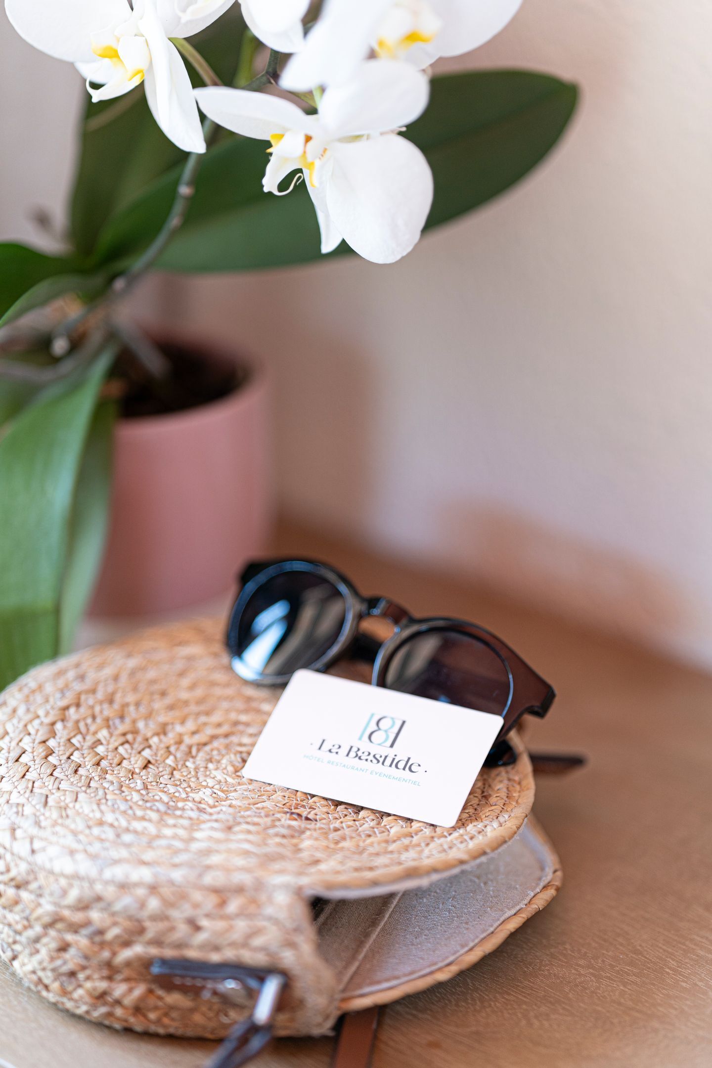 Un sac tressé, avec une paire de lunettes de soleil et une carte posée dessus.