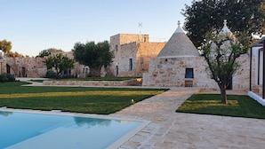 Um pátio com piscina, edifícios de pedra e uma árvore.