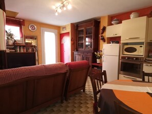 A kitchen with a dining area, wooden cabinets, a refrigerator, an oven, and a microwave.