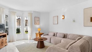 Ein modernes Wohnzimmer mit einem beigen Sofa, einem Holztisch und einem Fernseher auf einem Holzschrank.