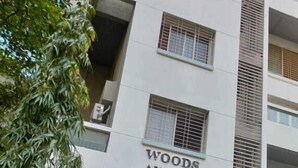Edifici de diversos pisos amb un rètol que diu "Woods A.P. PROJECT BY SHRI JEE DEVELOPERS".