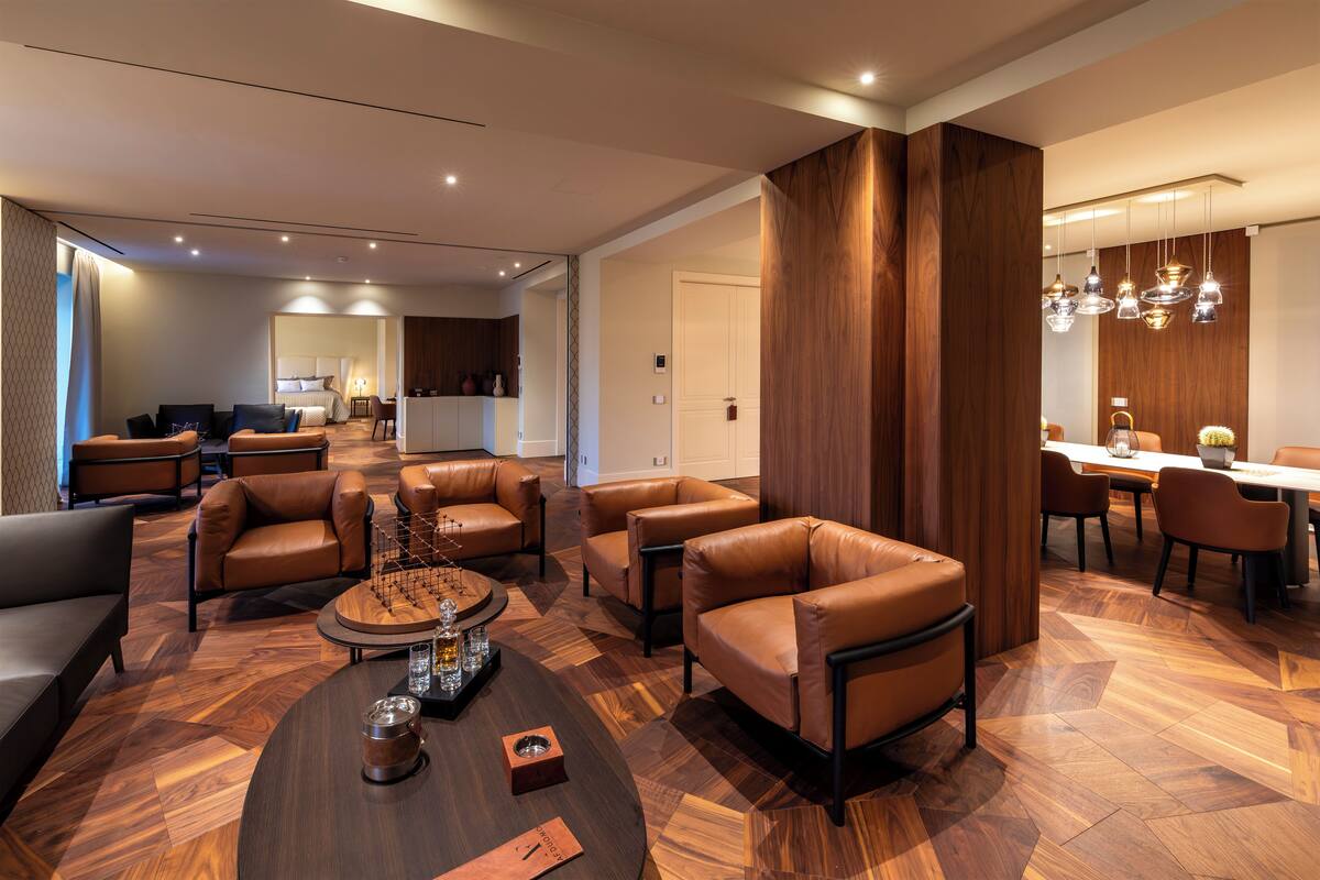 A modern living room with leather sofas, a coffee table, and a dining area with wooden flooring and pendant lights.