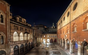 An indoor courtyard with arched walkways, a central fountain, and a dome structure in the background. - AF Duomo - Milano Luxury Suites (Milan)