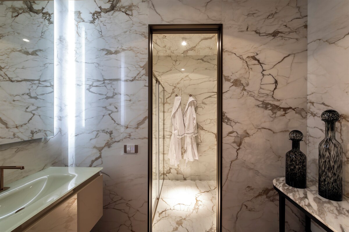 A bathroom with a marble floor, a glass-enclosed shower, and a sink with a modern faucet.