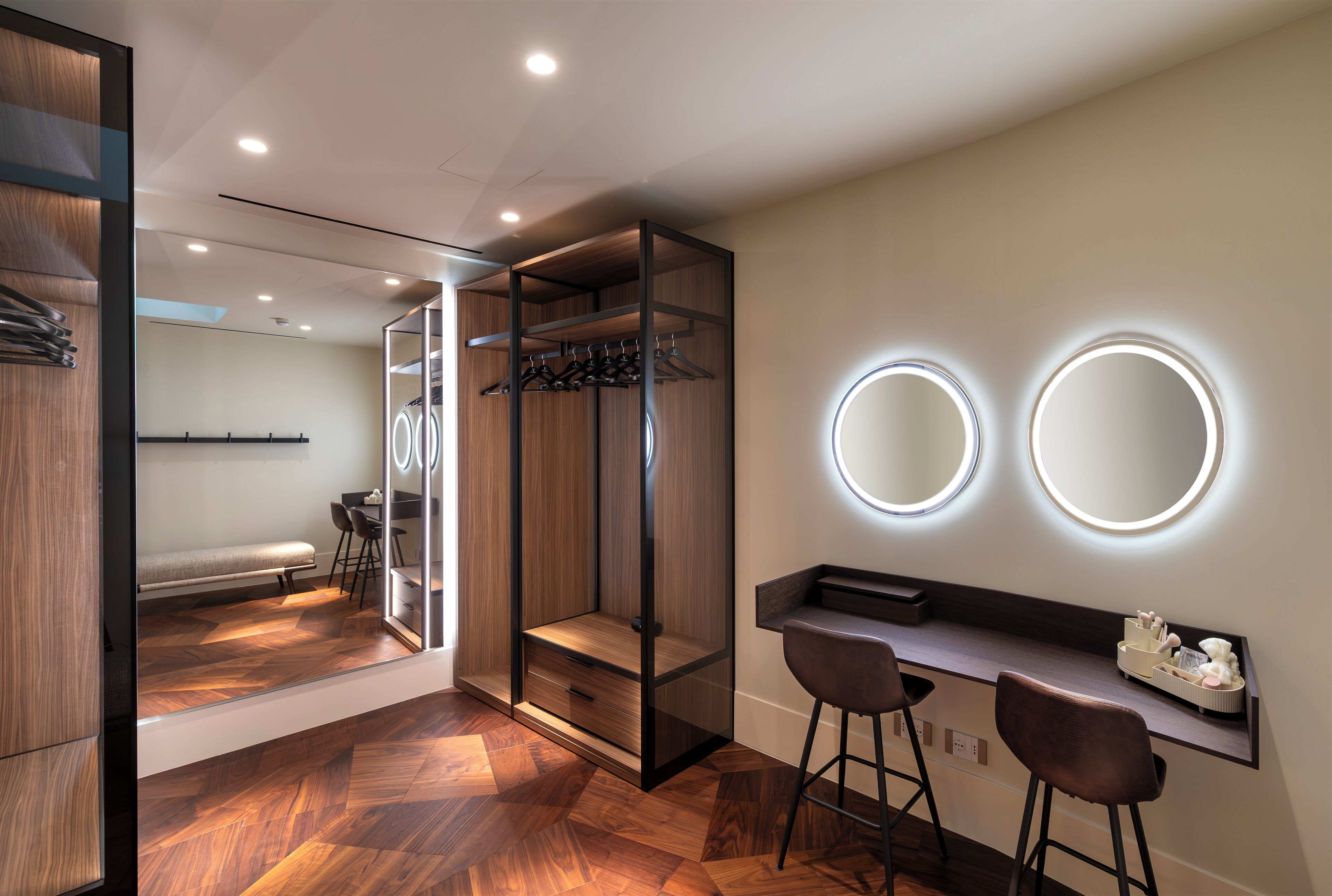 A modern bathroom with a vanity, two mirrors, and a bench.
