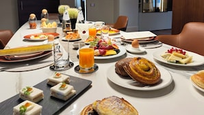 Ett matbord dukat med olika sorters frukostmat, inklusive bakverk, frukt och drycker.