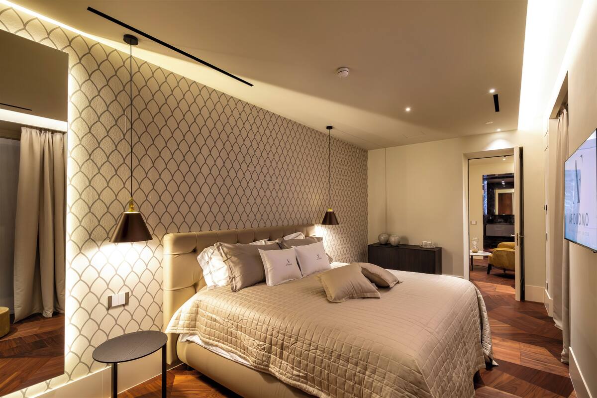 A modern bedroom with a large bed, a bedside table, and a nightstand.