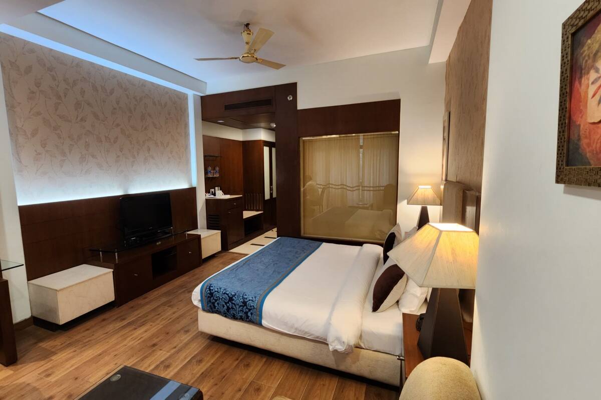 Una habitación de hotel moderna con una cama grande, televisión, escritorio y ventilador de techo.