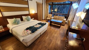 Habitación de hotel con una cama grande, un sofá, una mesita y vistas al exterior.