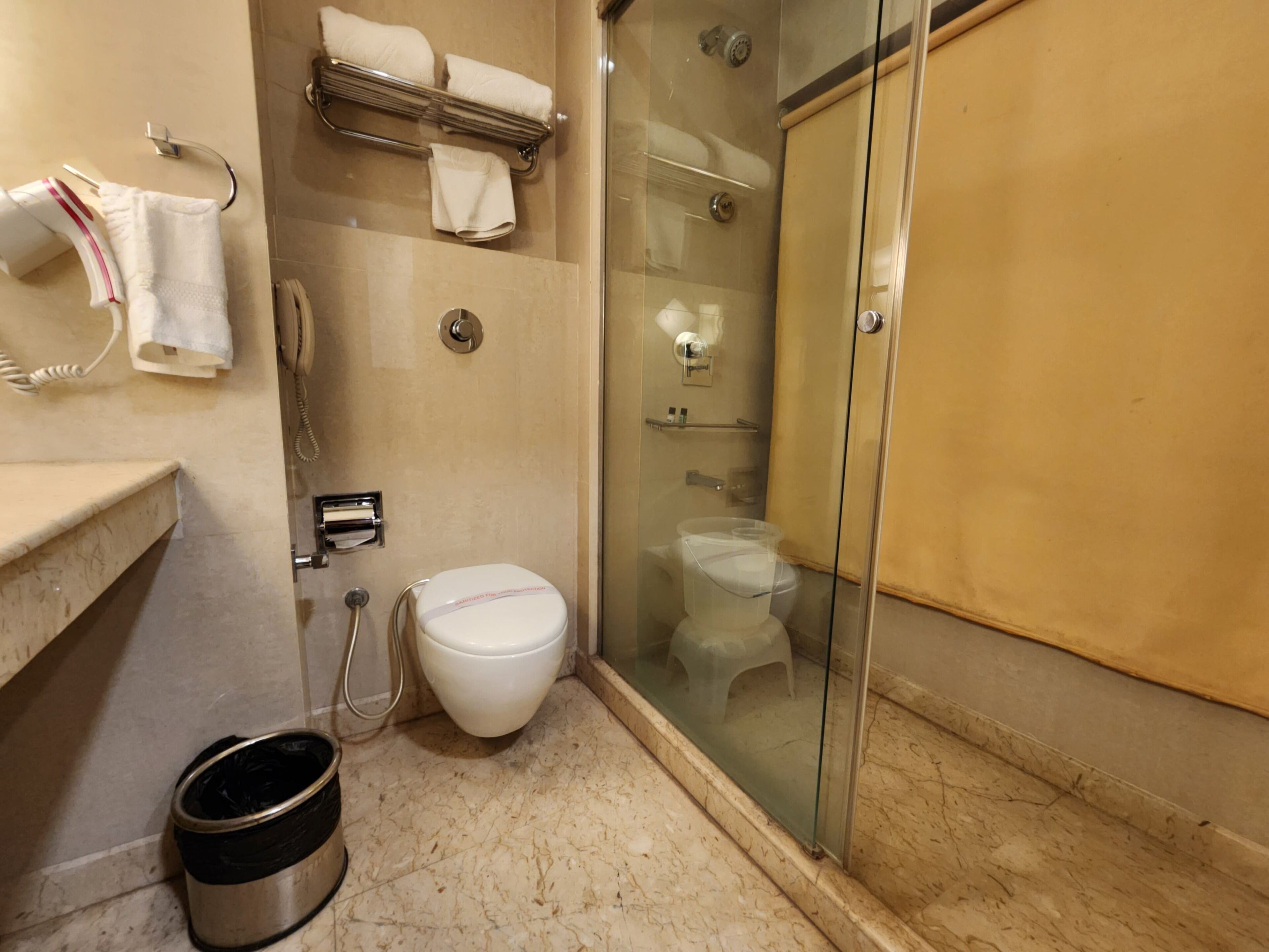 Un bagno con il water, box doccia in vetro e porta asciugamani con asciugamani.