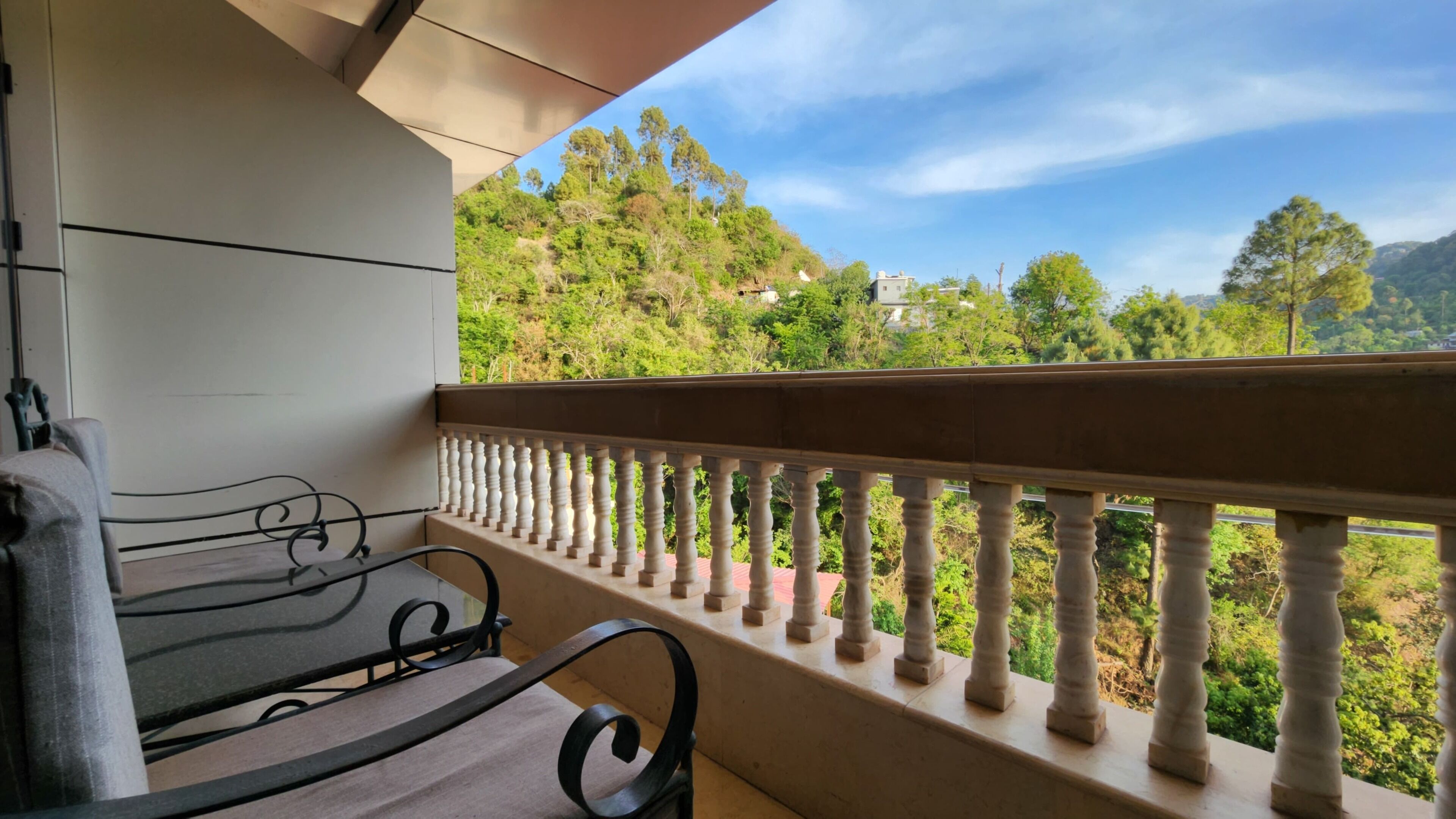 Ein Balkon mit Blick auf eine Hügellandschaft, einem Tisch und einem Stuhl.