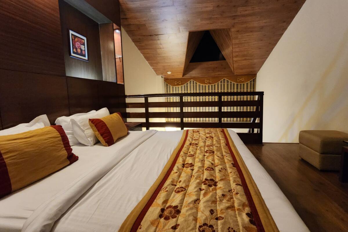 Habitación de hotel con una cama grande, cabecero de madera y una alfombra decorativa.