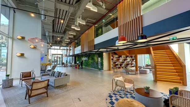 A spacious lobby with a high ceiling, modern furniture, and a staircase leading to an upper level.