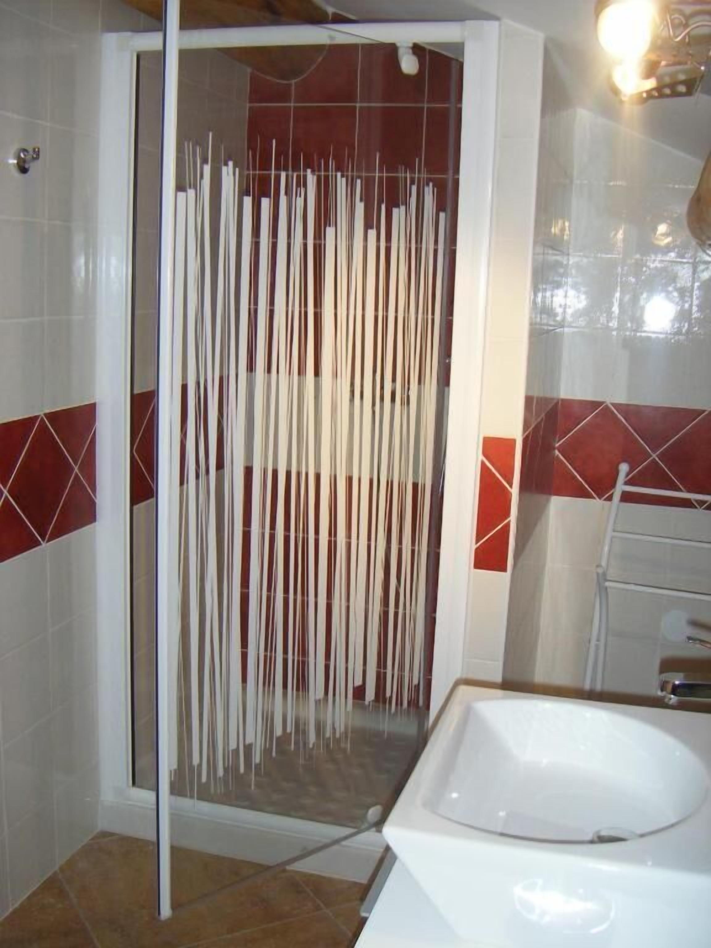 Un baño con cabina de ducha, lavamanos y paredes de azulejos.