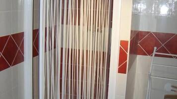 Un baño con cabina de ducha, lavamanos y paredes de azulejos.