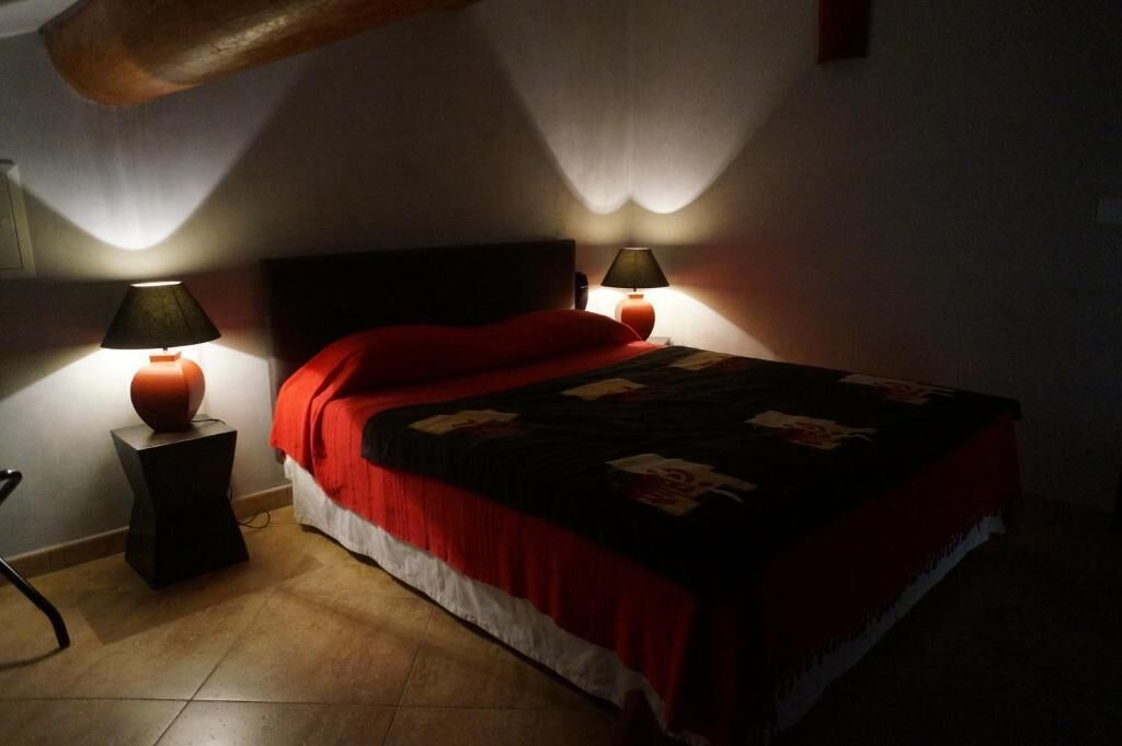 A bed with a red and black bedspread, two bedside lamps, and a wooden headboard.