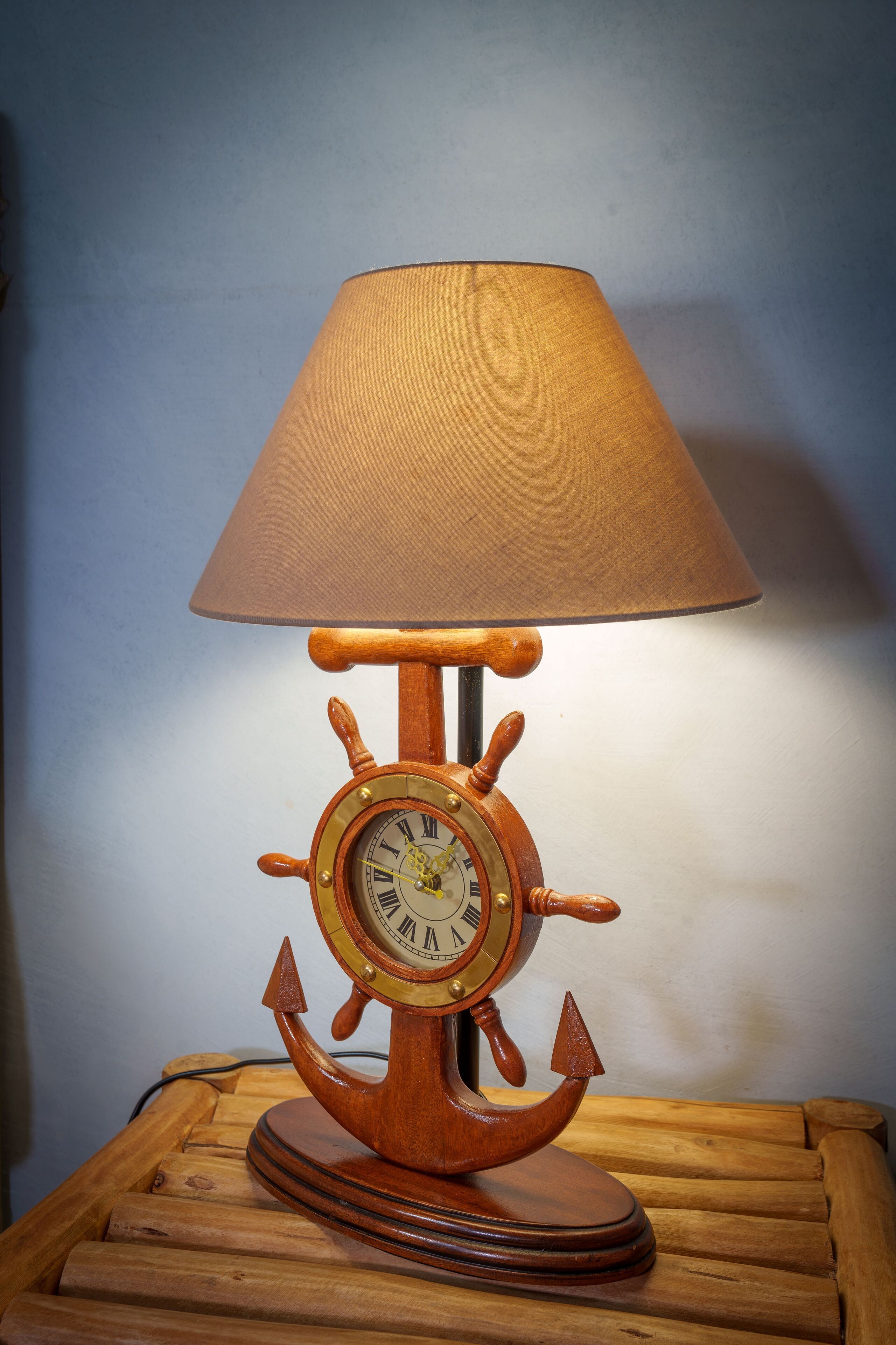 Een lamp in de vorm van een scheepsschroef met een beige lampenkap, staande op een houten tafel.