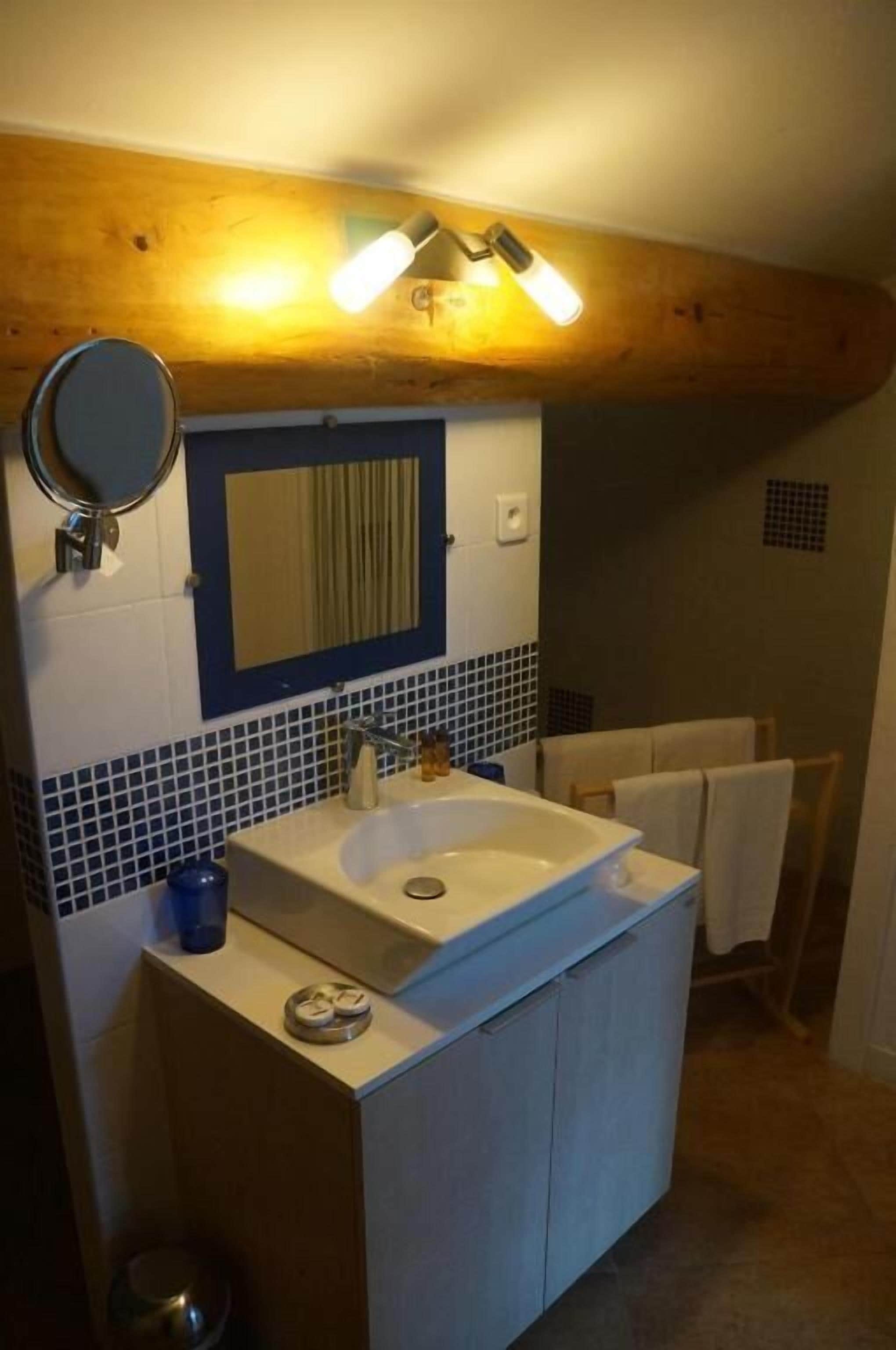 A bathroom with a sink, mirror, and towel rack.