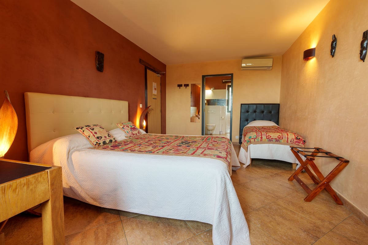 A hotel room with two beds, a wooden side table, and a small wooden chair.