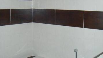 A bathroom with a bathtub, white and dark brown tiles, and a metal grab bar above the tub.
