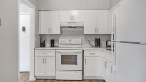 Une cuisine moderne avec des meubles blancs, un four encastré et un réfrigérateur.
