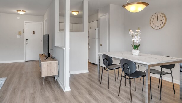 Une cuisine moderne avec des meubles blancs, un réfrigérateur et un coin repas comprenant une table et des chaises en marbre.