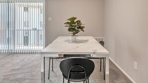 Ein stilvoller Essbereich mit einem Marmortisch, schwarzen Stühlen und einer Zimmerpflanze.