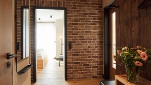 An interior with a brick wall, a wooden floor, a bed in the background, and a vase with flowers on a table. - Binnendiek Resort Büsum Haus 4 - Apartment 1 (Büsum)